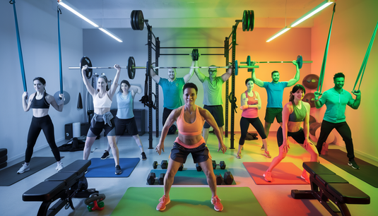 A diverse group of people energetically engaging in a home workout session in a modern, well-lit room using various fitness equipment.